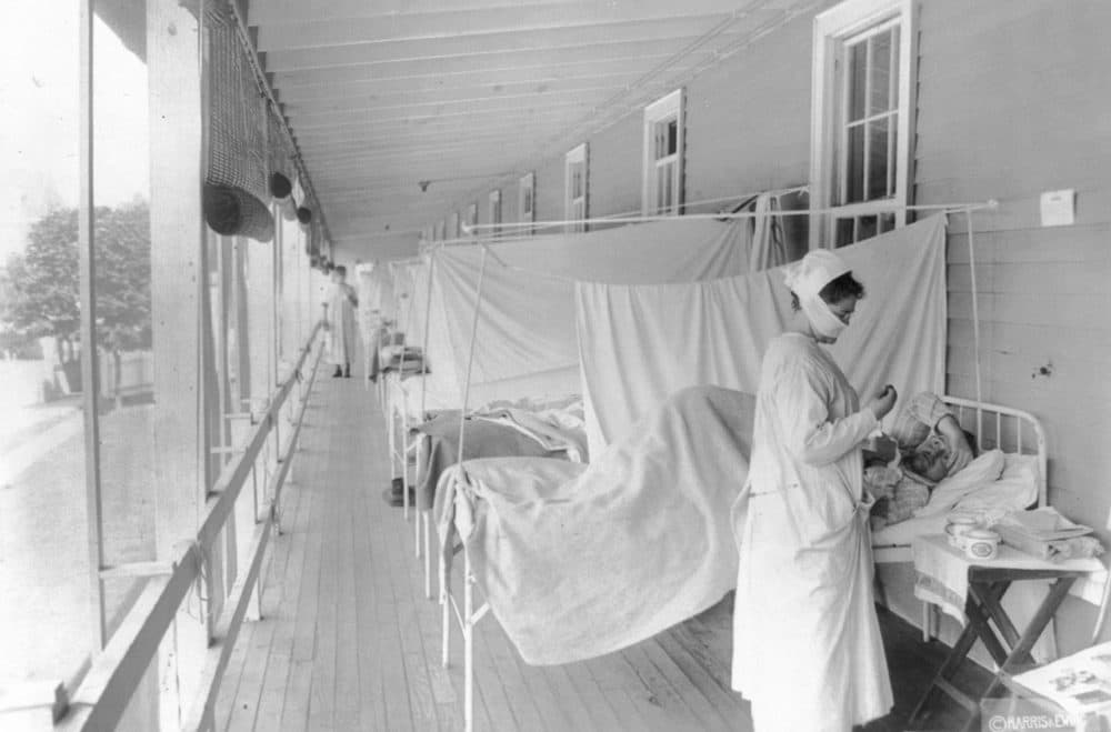 In this November 1918 photo made available by the Library of Congress, a nurse takes the pulse of a patient in the influenza ward of the Walter Reed hospital in Washington. (Harris Ewing/Library of Congress via AP)