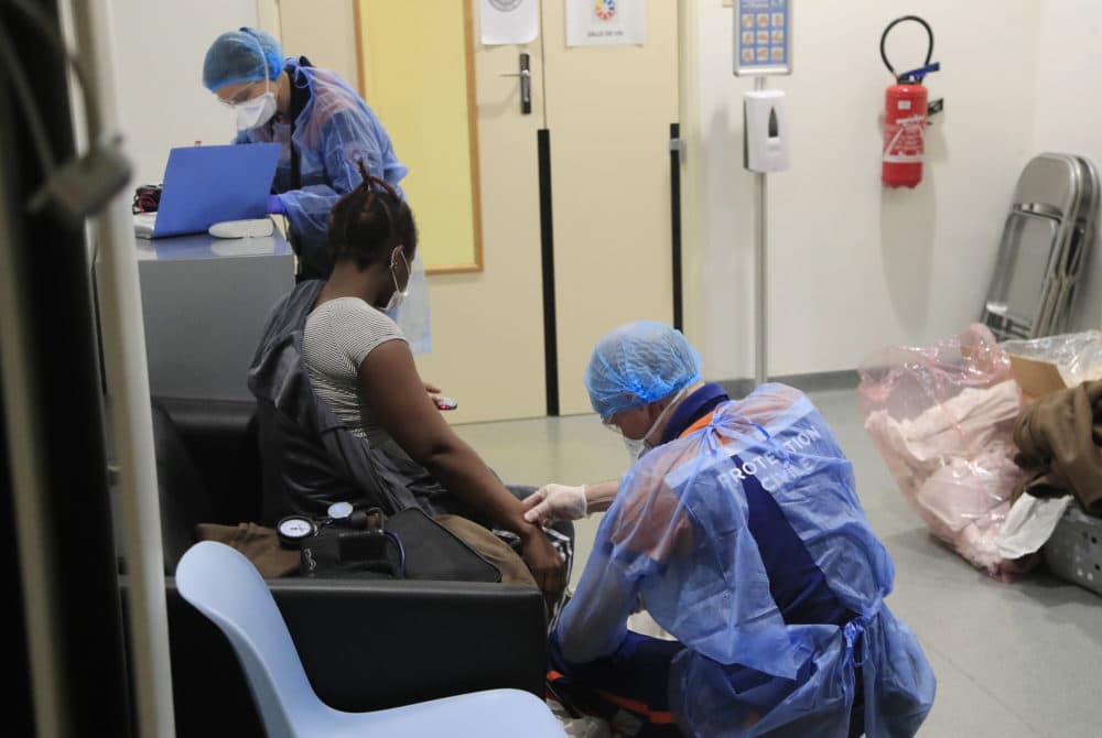 A member of the Civil Protection service checks the pulse of a 27-year-old pregnant woman suspected of being infected with COVID-19 in Paris. (Michel Euler/AP)
