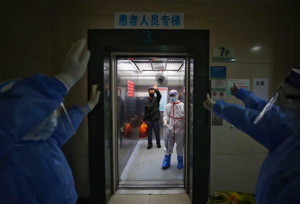 Medical staff wave goodbye to a recovered COVID-19 coronavirus patient at the Red Cross Hospital in Wuhan in China's central Hubei province on March 16, 2020. (STR/AFP via Getty Images)