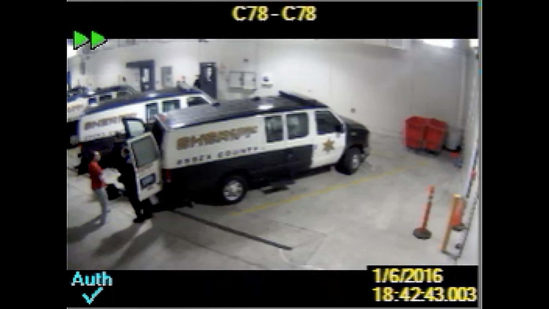 A screenshot from jail video shows Sam Dunn, in the red shirt, being loaded into a transport van to go to a Bridgewater treatment center. (Essex County sheriff’s office)