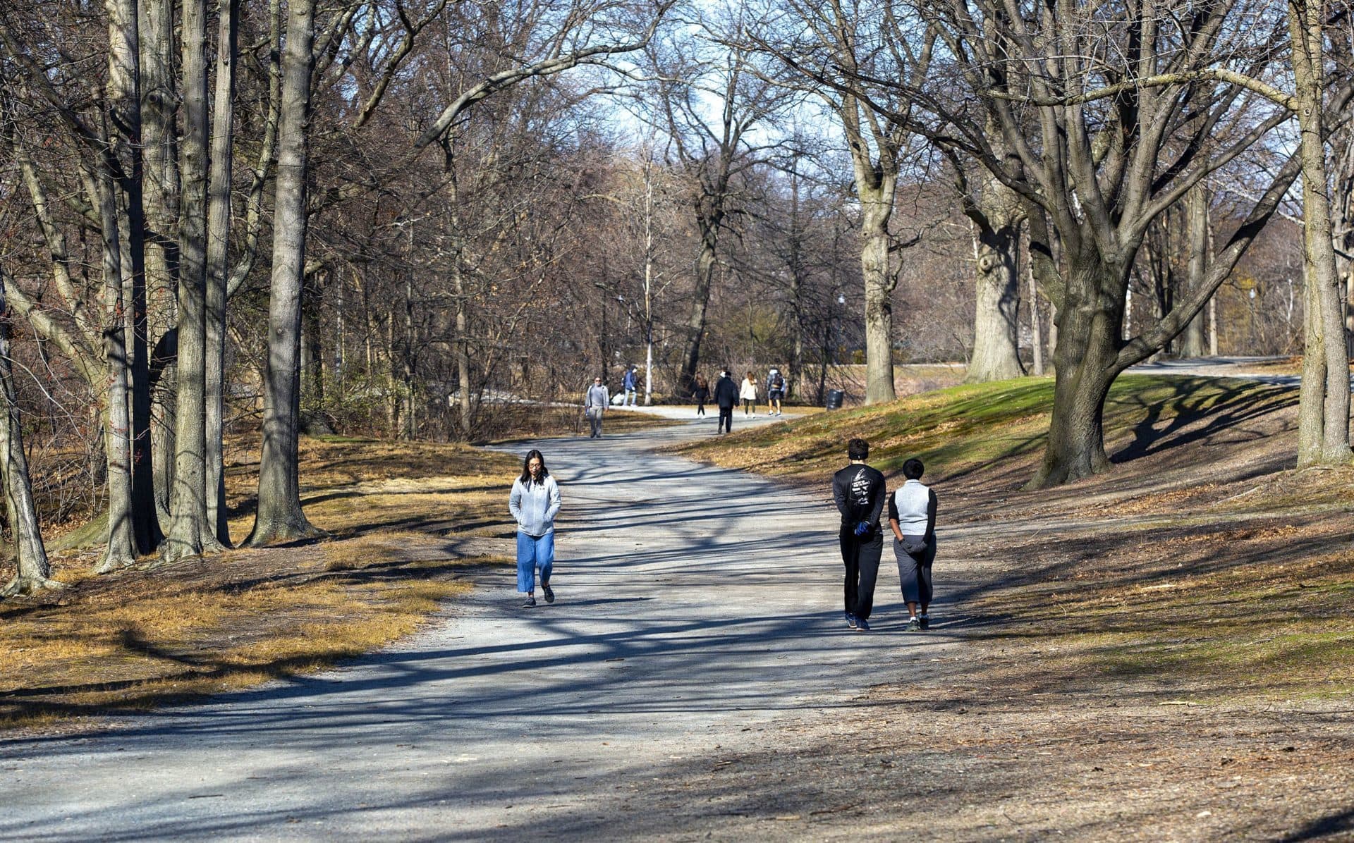 Keeping at least 6 feet of distance from others, walkers make their way along a path in the Fenway. (Robin Lubbock/WBUR)