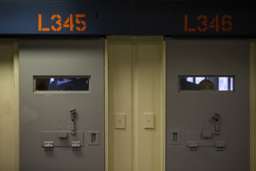 Inmates peer through the windows behind cell doors inside the Worcester County jail. (Jesse Costa/WBUR)