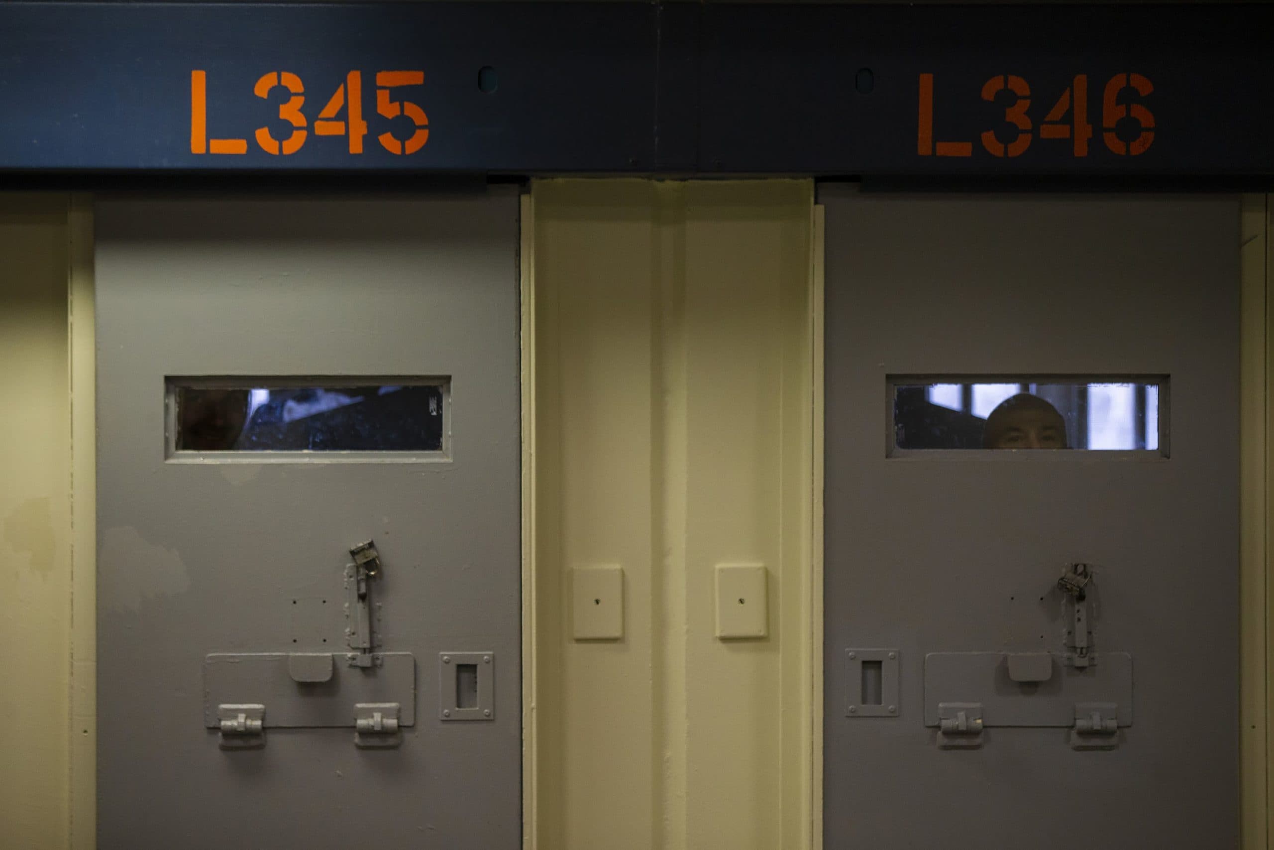 Inmates peer through the windows behind cell doors inside the Worcester County jail. (Jesse Costa/WBUR)