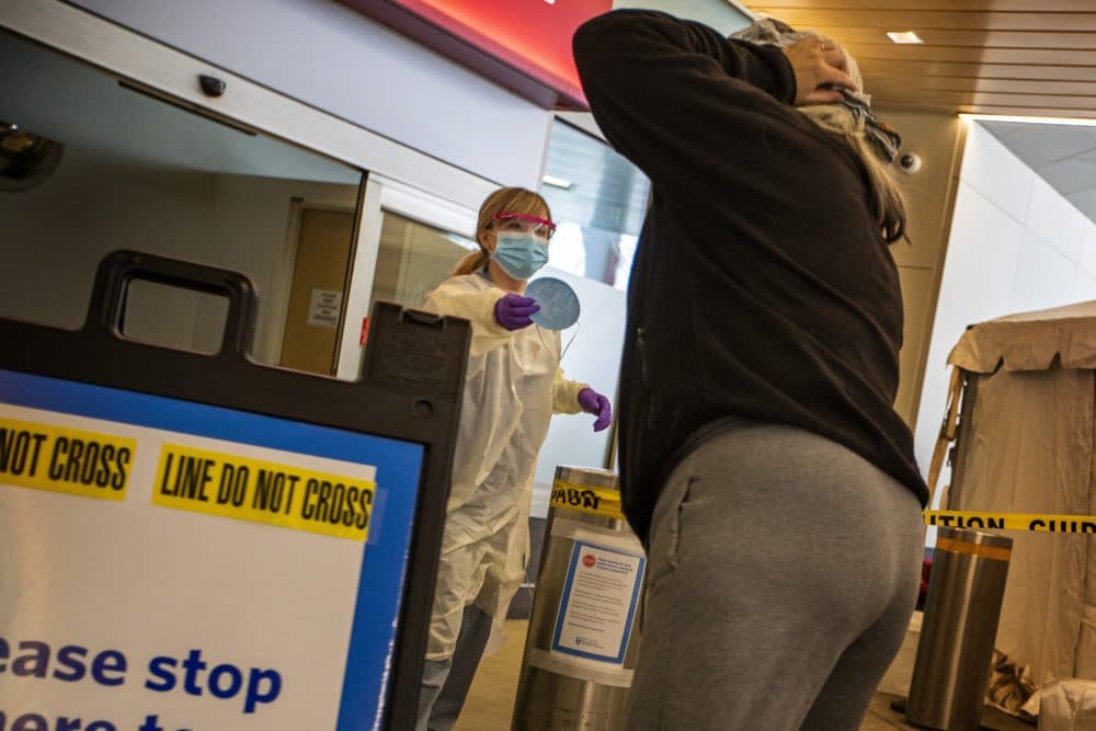 A health care worker hands a mask to someone wanting to be tested for COVID-19 at a testing tent at Brigham and Women’s Hospital. (Jesse Costa/WBUR)