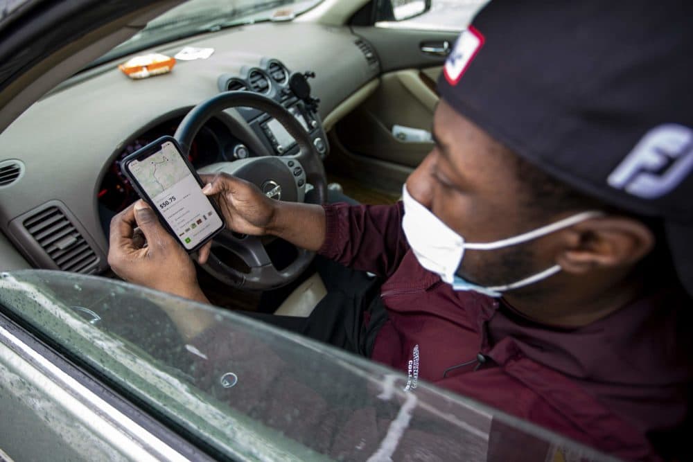 In his car at Costco in Dedham, Instacart shopper Shamar Martin looks at a double order on the Instacart app. (Jesse Costa/WBUR)