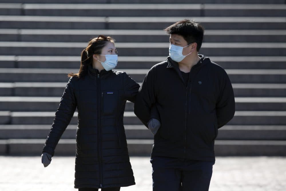 A couple wears protective masks while walking at Faneuil Hall, Saturday, April 4, 2020, in Boston. (AP Photo/Michael Dwyer)