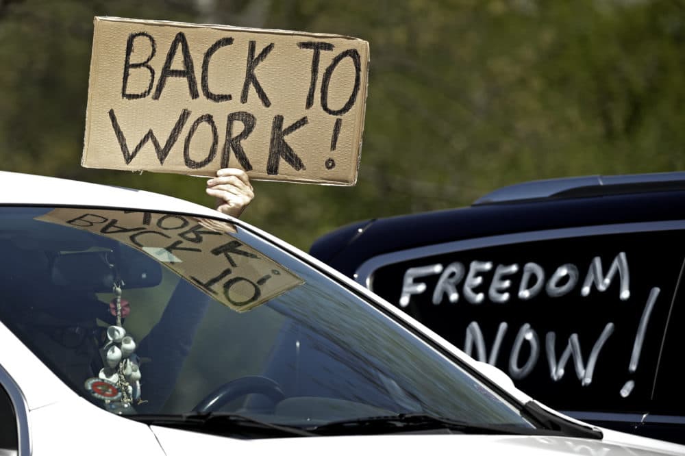 A man holds a sign as he drives past a rally to protest stay-at-home orders put into place due to the COVID-19 Thursday, April 23, 2020, outside the Statehouse in Topeka, Kan. Several hundred gathered to protest the restrictions and urge the reopening of businesses closed in an effort to slow the spread of the coronavirus . (Charlie Riedel/AP)