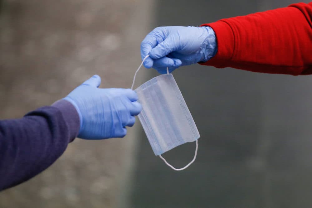A Red Cross volunteer wearing gloves distributes masks to a commuter in Barcelona, Spain. (Pau Barrena/AFP/Getty Images)