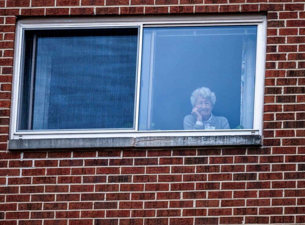 A resident of the Goodwin House senior living community, looks on as she listens to the DC area motown band "The Tribe" play a social distance concert in their parking lot in Arlington, Virginia, during the coronavirus pandemic on April 14, 2020. (ANDREW CABALLERO-REYNOLDS/AFP via Getty Images)