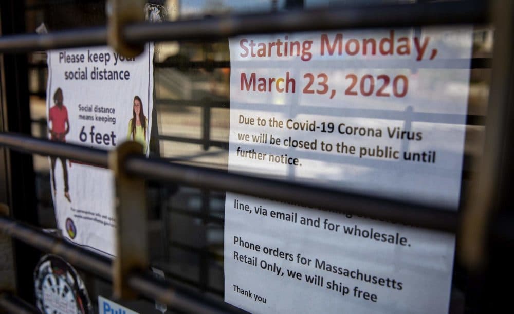 In mid-May a rolling security grille remains closed over the entrance to Woodway Darts and Supplies in Somerville. (Robin Lubbock/WBUR)