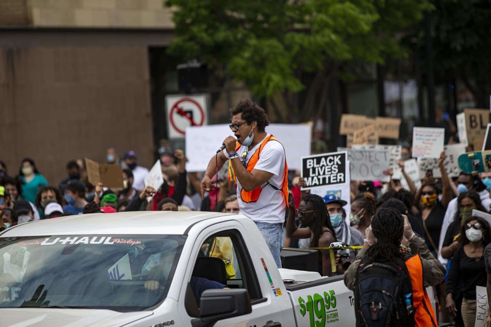 Standing in the back of a rental pickup, Mass. Action Against Police Brutality organizer Brock Satter leads protesters down Washington Street. (Jesse Costa/WBUR)