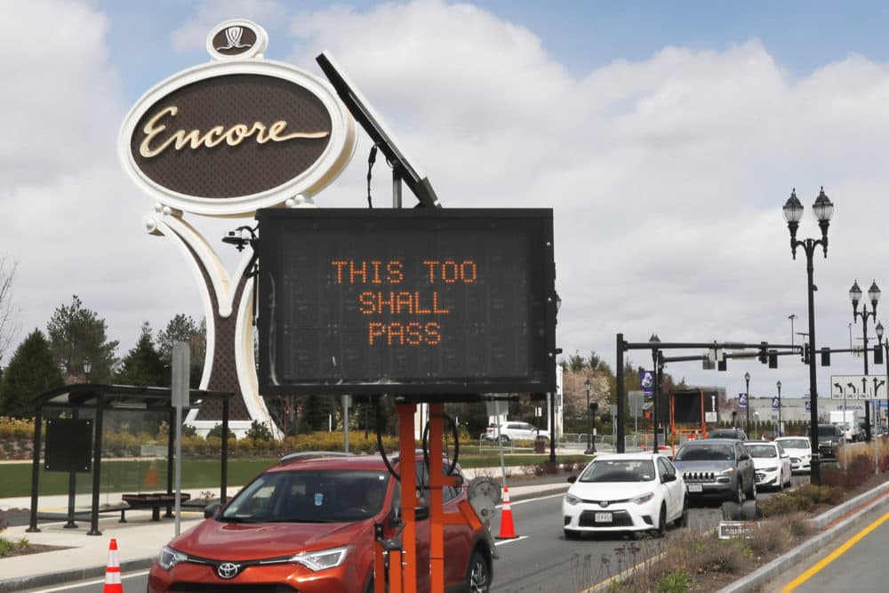 A roadway sign reads "THIS TOO SHALL PASS" as cars pass the entrance leading to the Encore Boston casino in Everett, Mass., April 22, 2020. (Charles Krupa/AP)