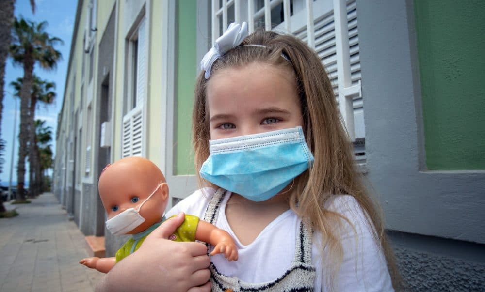 Naidelin, 5, and her doll pose wearing a face mask in the street in Santa Cruz on the Canary Island of Tenerife, on April 26, 2020 during a national lockdown to prevent the spread of the COVID-19 disease.(DESIREE MARTIN/AFP via Getty Images)