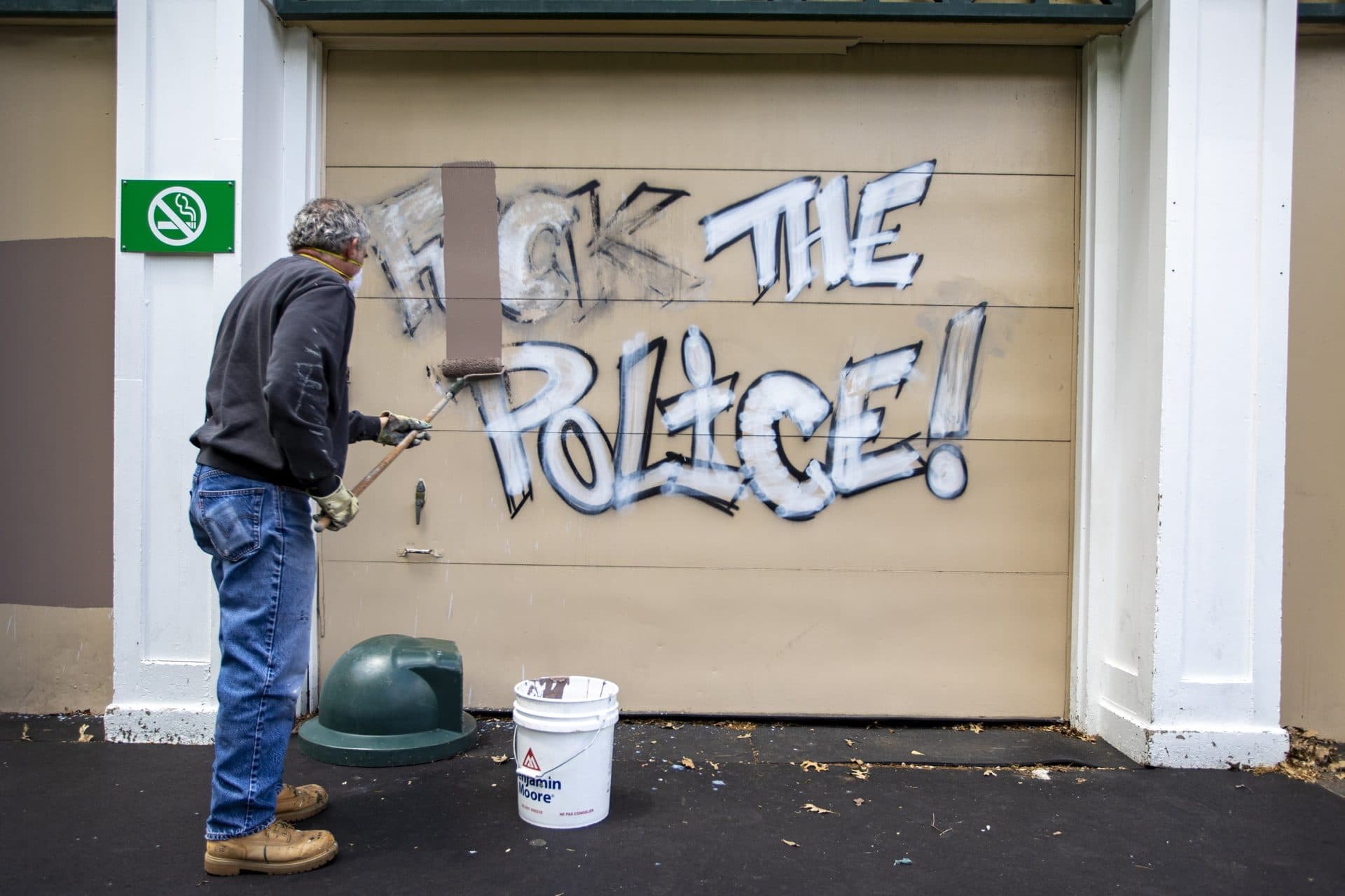 A Boston Parks and Recreaton worker paints over graffiti on a wall of the Frog Pond Pavilion in the Boston Common. The graffiti was sprayed following an anti-police brutality protest at the Massachusetts State House. (Jesse Costa/WBUR)