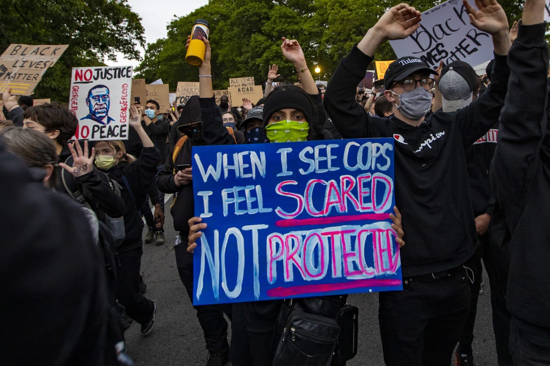 Protesters follow police down Circuit Road toward Forest Hills Station. (Jesse Costa/WBUR)