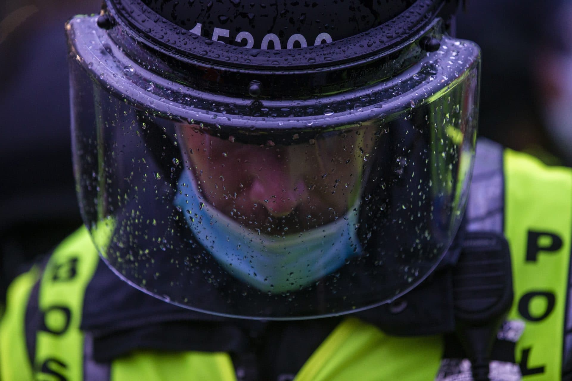A Boston Police officer looks down as protesters surround them in front on Forest Hills Station. (Jesse Costa/WBUR)