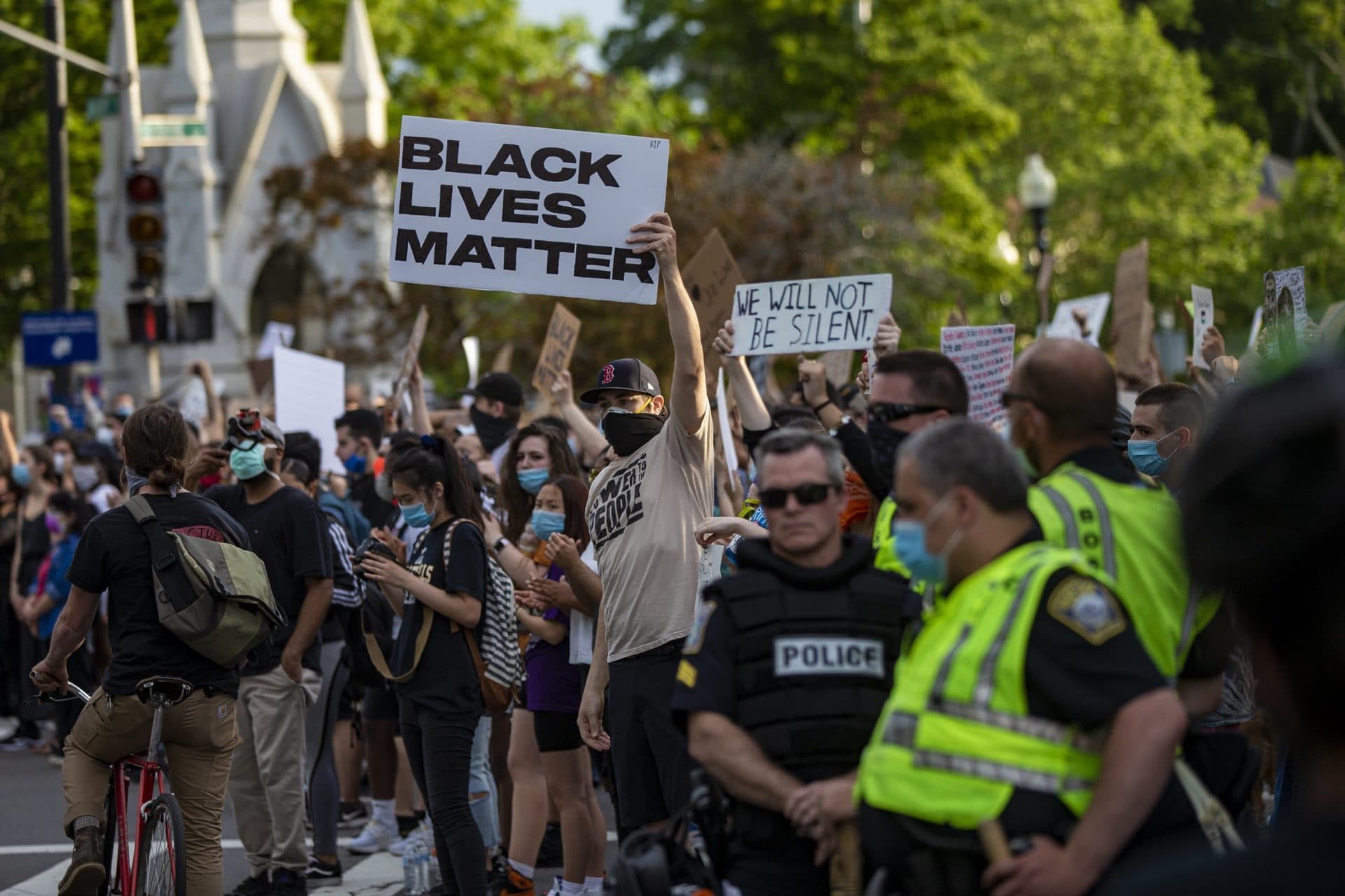 Police stand by and watch as hundreds of protesters gather at the Soldier’s Memorial in Jamaica Plain for the vigil. (Jesse Costa/WBUR)