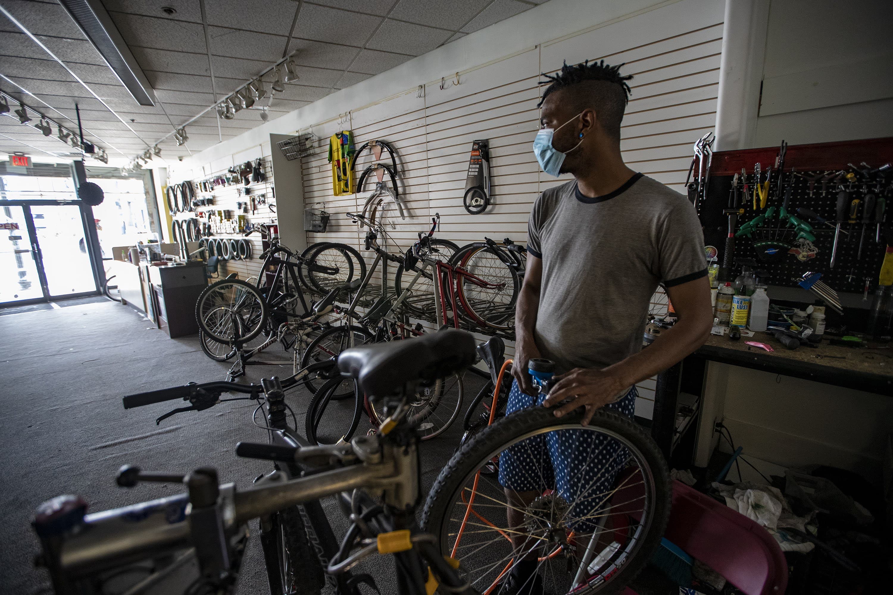 Noah Hicks looks out to the front of his bicycle shop, Spokehouse, while repairing a tire for a customer. (Jesse Costa/WBUR)