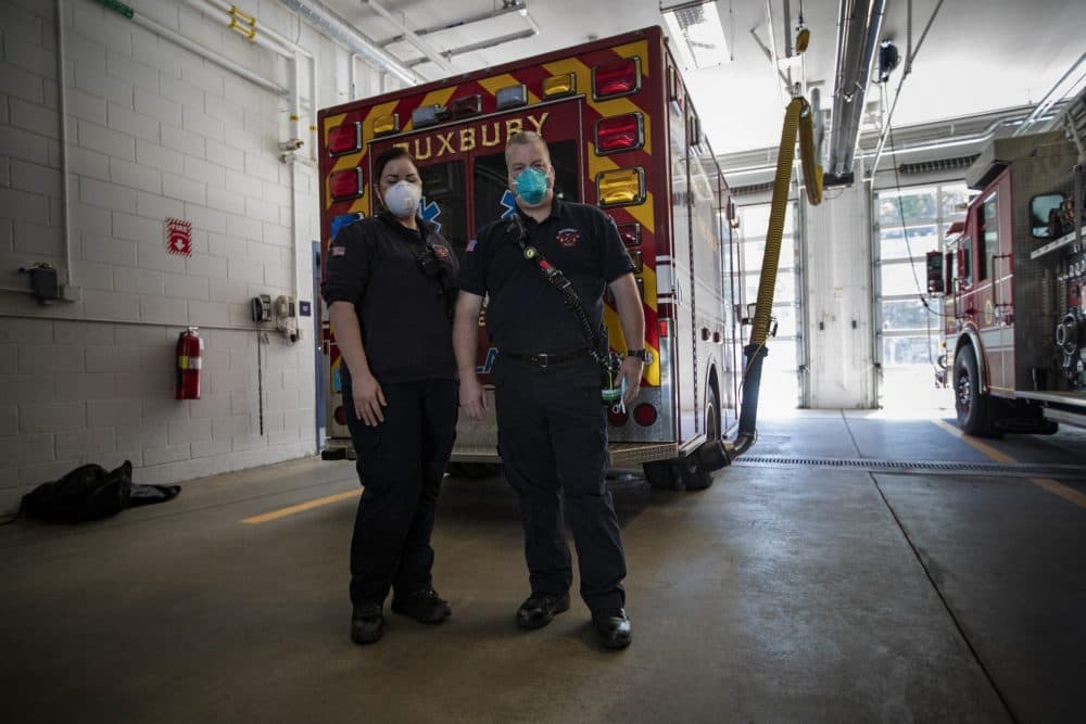 Paramedics Jen Baldock and Justin Stratton get back from a call earlier in the morning at the Duxbury Fire Department. They are wearing masks that were procured from MEMA after a shipment of faulty ones were delivered to them. (Jesse Costa/WBUR)