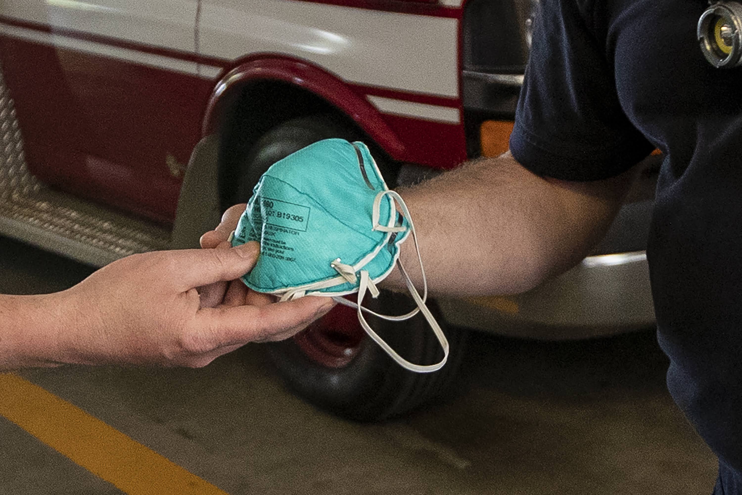 Duxbury Fire Chief Joe Reardon hands N95 masks to paramedic Justin Stratton after he returns from a call. (Jesse Costa/WBUR)