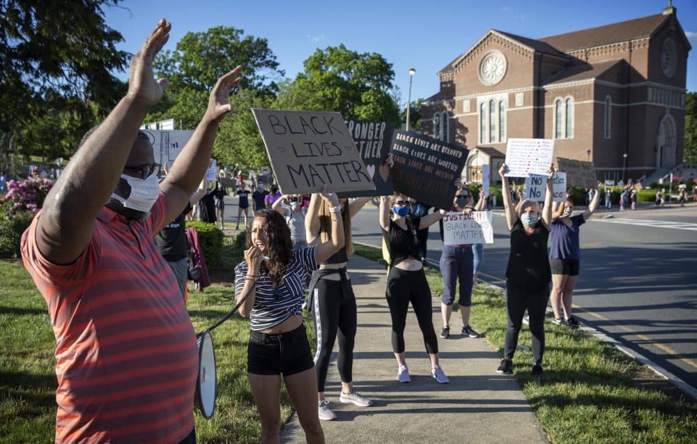 Tito Jackson holds up his hands after handing over the microphone to a protester to lead the chant. (Robin Lubbock/WBUR)