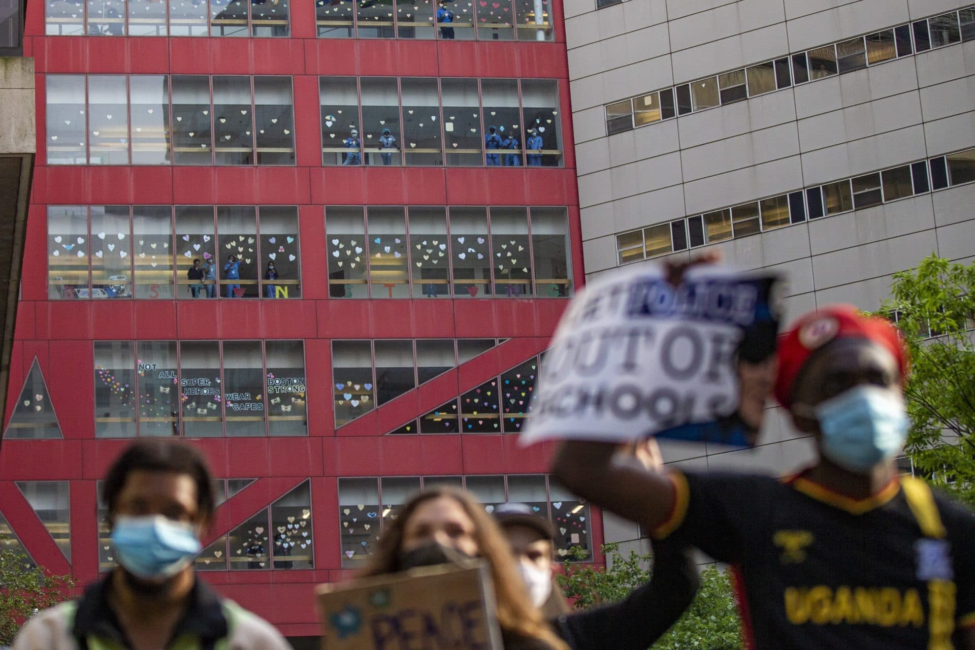 Medical Staff watch through the windows of Tufts Medical Center as hundreds of protesters march up Washington Street en route to Boston City Hall during the F.T.P. March to Defund Police and Fund Our Communities. (Jesse Costa/WBUR)