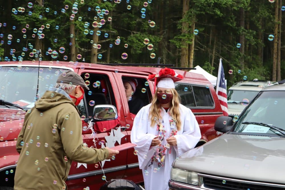 Port Townsend High School senior Torianna Minnihan received her diploma -- and a bubble shower -- at a graduation ceremony held at the local drive-in movie theater on June 12, 2020. (Tom Banse/Northwest News Network)