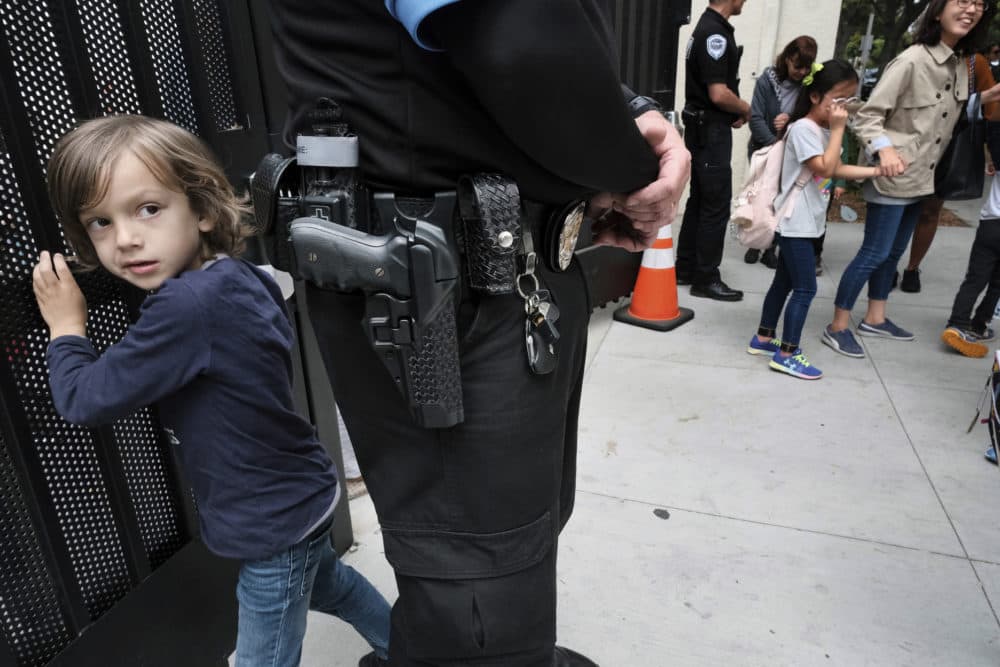 Julian Richner, 9, leaves school for the day to meet his mother as he passes behind an armed security guard at Beverly Hills Unified School District's K-8 Horace Mann School in Beverly Hills, Calif. on Monday, May 13, 2019. Districts nationwide are employing a multi-layered approach for safety that combines mental health programs, bullying prevention initiatives with hardware and software technology, as well as armed and unarmed security officers. (Richard Vogel/AP)