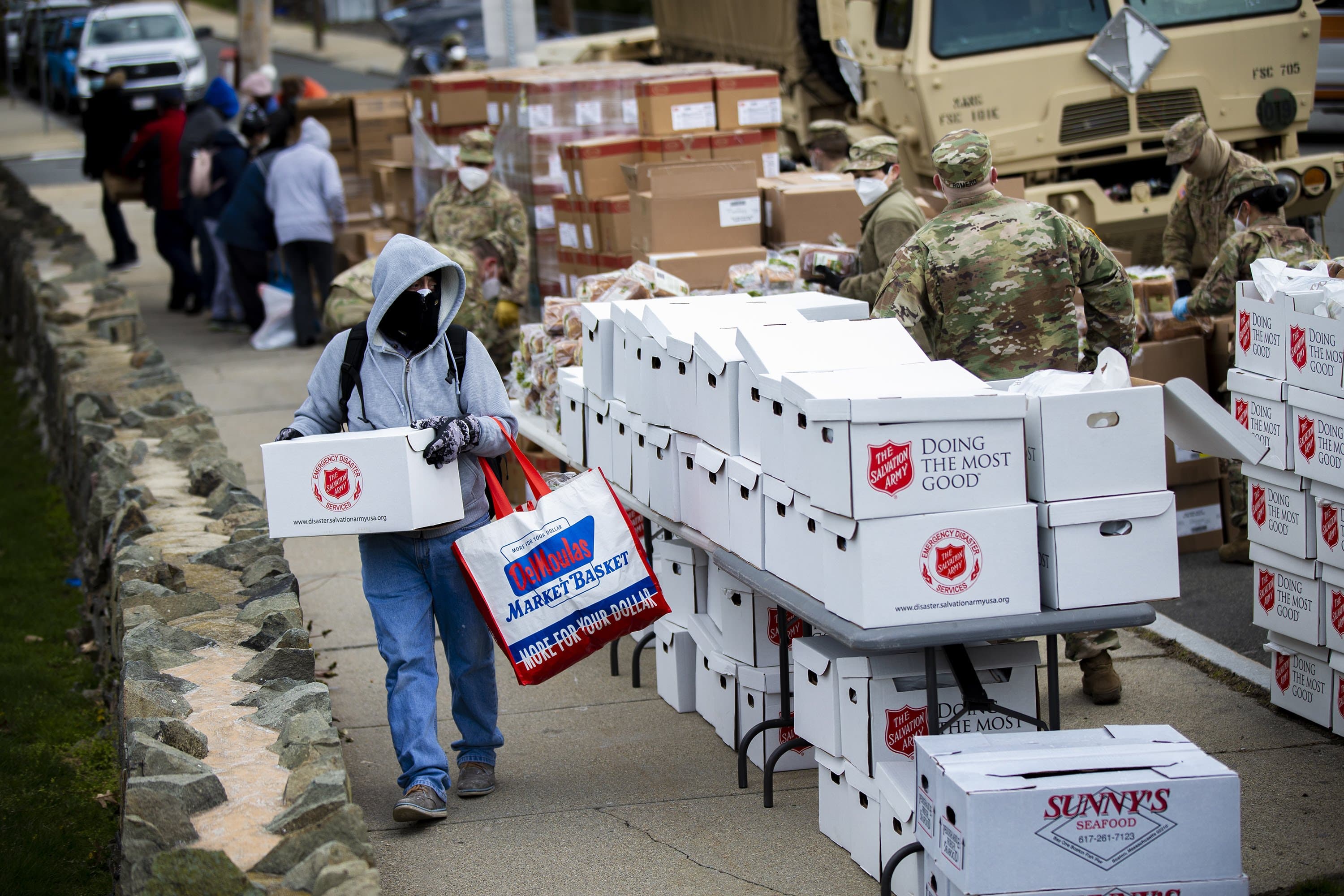 A Chelsea resident carries a box of food supplies during a pop-up food pantry at Washington Park in April, 2020. (Jesse Costa/WBUR)