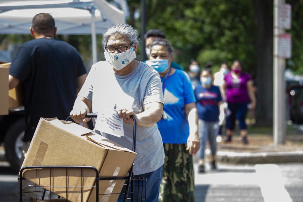 Chelsea, an environmental justice community, has been hard hit by the coronavirus pandemic. In this photo, residents line up to receive boxes of food supplies at a food pantry in Chelsea Square. (Jesse Costa/WBUR)