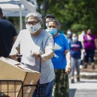 Chelsea, an environmental justice community, has been hard hit by the coronavirus pandemic. In this photo, residents line up to receive boxes of food supplies at a food pantry in Chelsea Square. (Jesse Costa/WBUR)