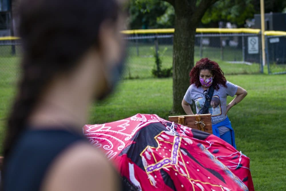 Diana Bernard reads the "South - Learning" plaque, a part of the Lilly Manycolors art installation “The Red Dress Lodge” as the artist looks on. The art installation is meant to bring awareness of murdered and missing indigenous womxn and girls and is on display at the Boston Common. (Jesse Costa/WBUR)