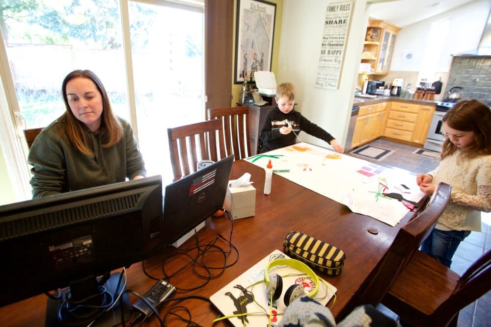 In this Tuesday, March 17, 2020 photo Kim Borton, left, works from home while her children Logan Borton, center, age 6 and Katie Borton, age 7, as they work on an art project in Beaverton, Ore. (Craig Mitchelldyer/AP Photo)