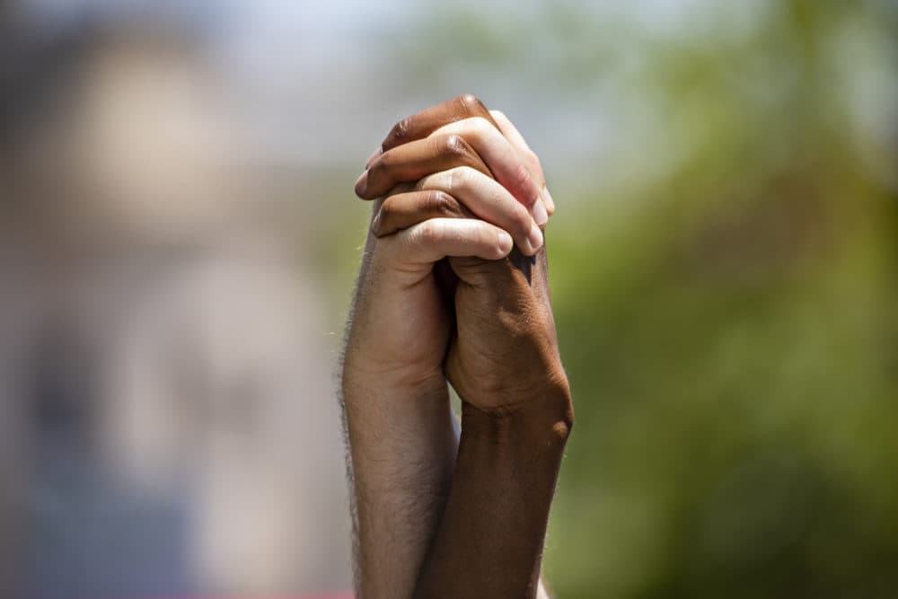 Two men hold their interlaced hands in the air as they march with other members and allies of the LGBTQ community to the White House as part of the Pride and Black Lives Matter movements on June 13, 2020 in Washington, D.C. (Samuel Corum/Getty Images)