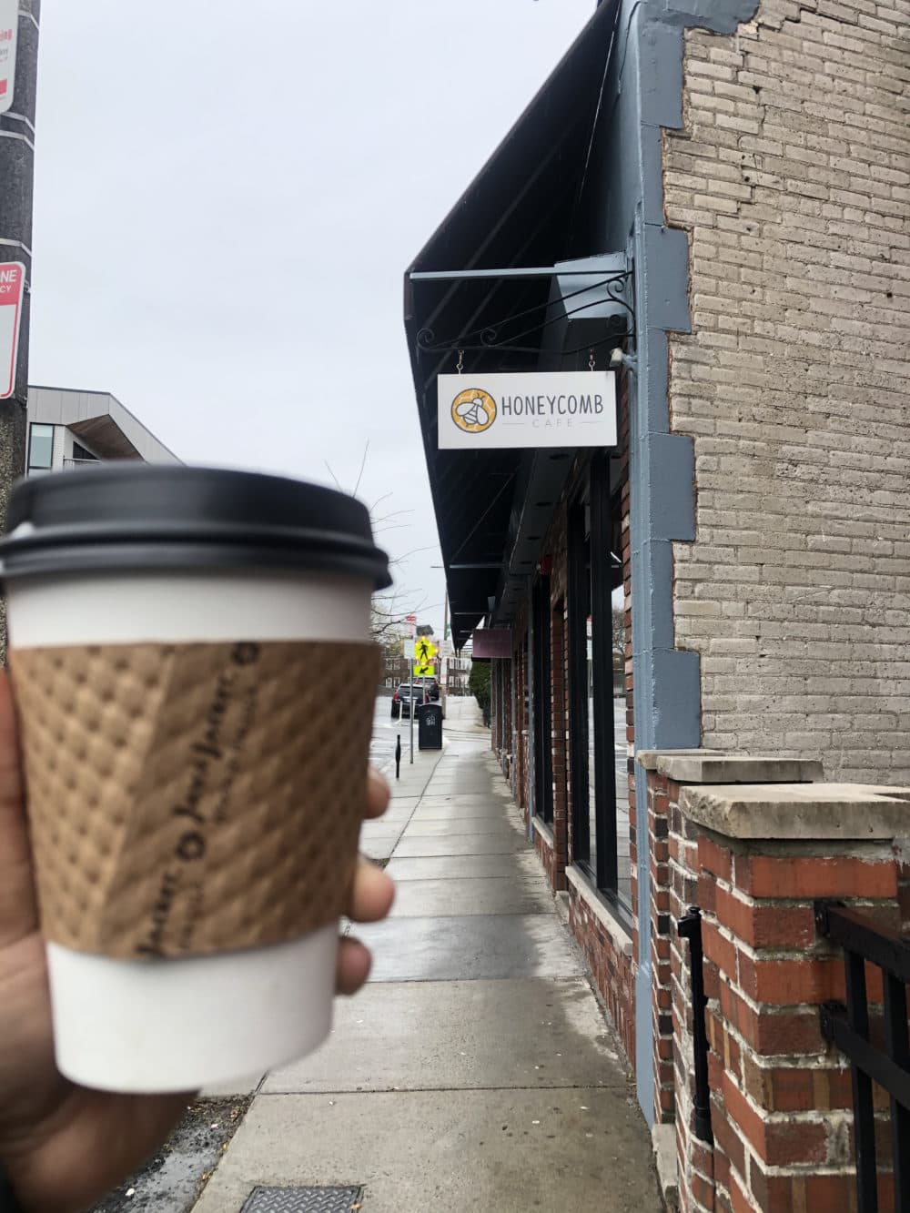 Christian holds up a cup of coffee from one of her favorite local shops, Honeycomb Cafe in Dorchester.