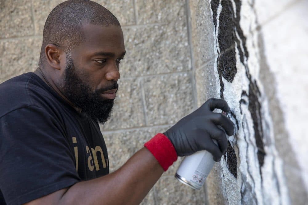 Rob "Problak" Gibbs works on a reference to Rob Stull's art in the "Breathe Life" mural at Madison Park Technical Vocational High School. (Robin Lubbock/WBUR)