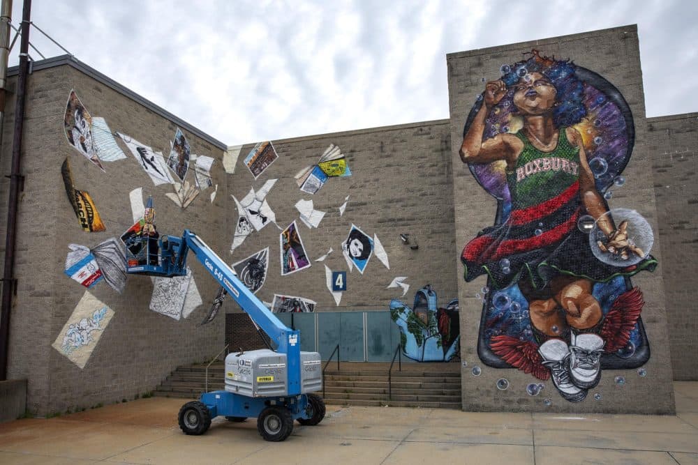 Rob "Problak" Gibbs works on the third wall of the "Breathe Life" mural at Madison Park Technical Vocational High School, as the project nears completion. (Robin Lubbock/WBUR)