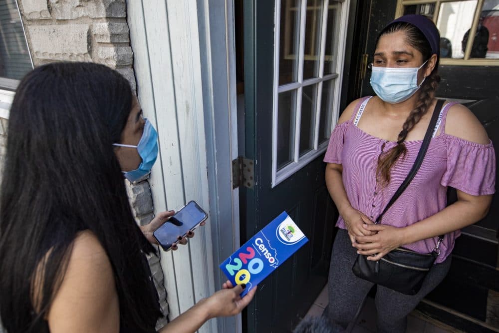 La directora del Centro Presente, Patricia Montes, le explica a Angélica la importancia de completar el censo de 2020 mientras entrega alimentos a las familias necesitadas en East Boston. (Jesse Costa/WBUR)
