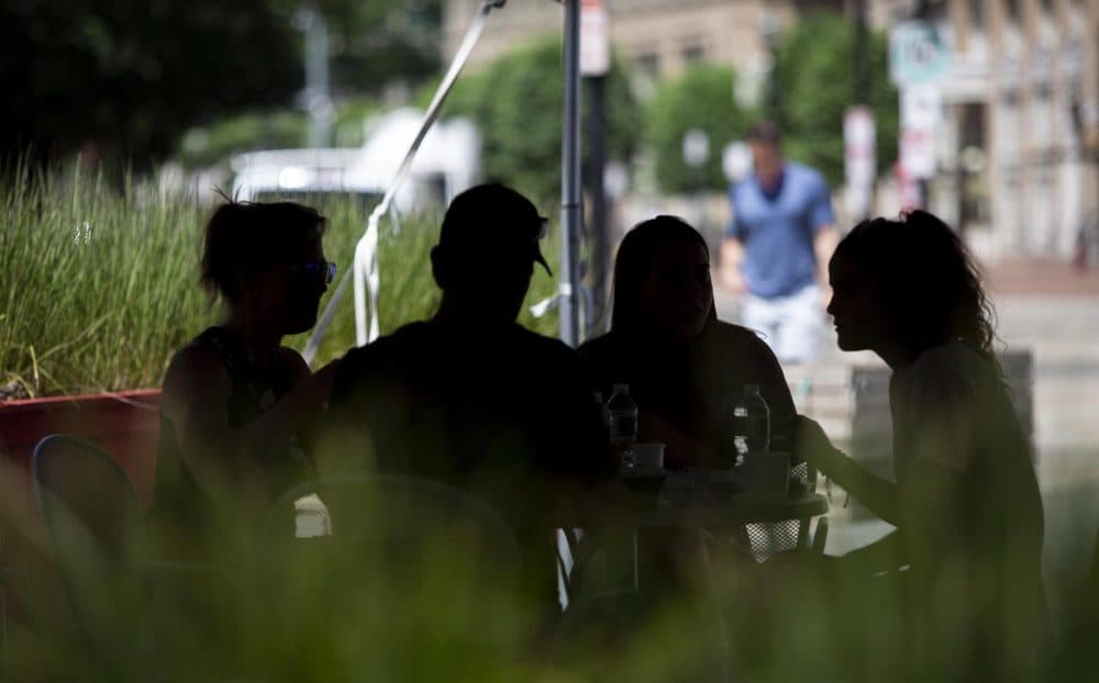 Guests eat in the shade outside James Hook & Co on Atlantic Avenue, Boston. (Robin Lubbock/WBUR)