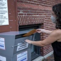 A Massachusetts voter places her vote into the Cambridge ballot dropbox ahead of the state primary. (Robin Lubbock/WBUR)