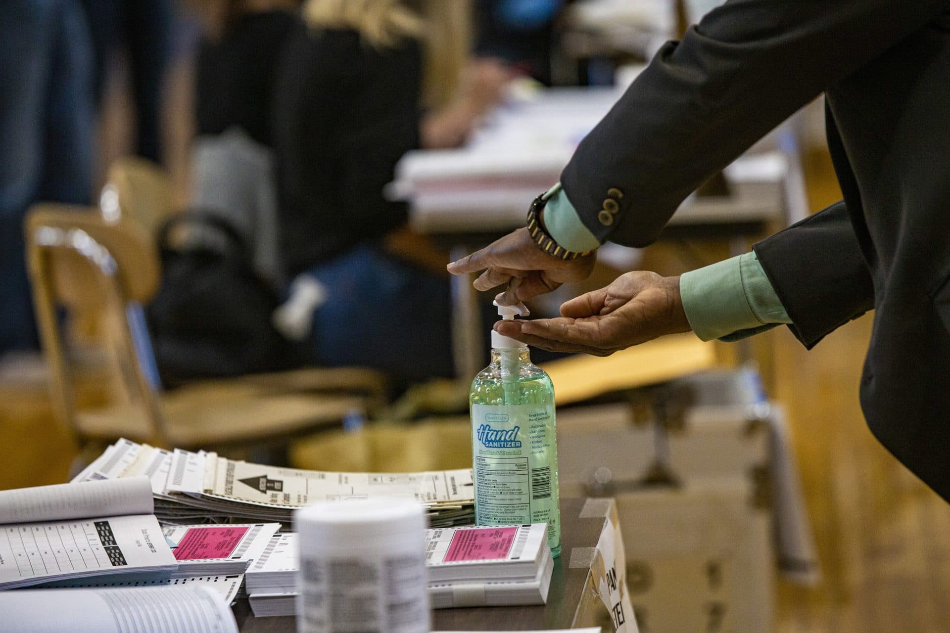 A voter uses hand sanitizer before accepting his ballot at Ward 1 in East Boston High School. (Jesse Costa/WBUR)