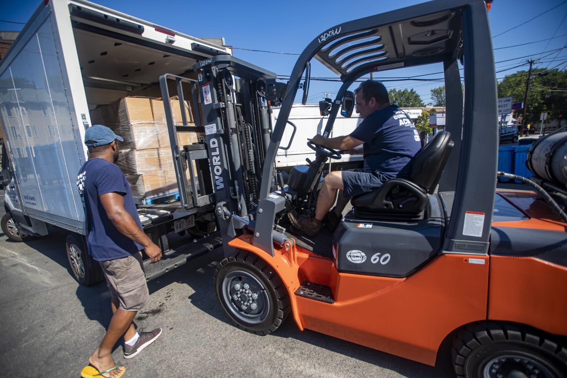 Workers use a forklift to pack a box truck for delivery. (Jesse Costa/WBUR)