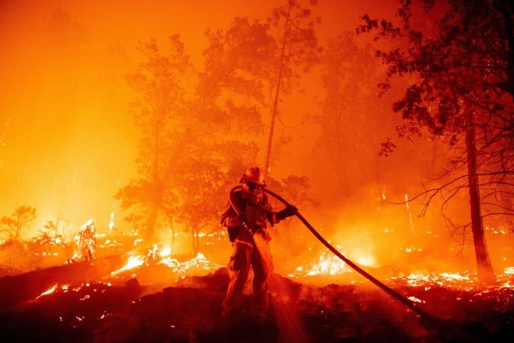 A firefighter douses flames as they push toward homes during the Creek fire in Madera County, California, on September 7, 2020. A firework at a gender reveal party triggered a wildfire in southern California that has destroyed 7,000 acres and forced many residents to flee their homes. (Josh Edelson/AFP/Getty Images)