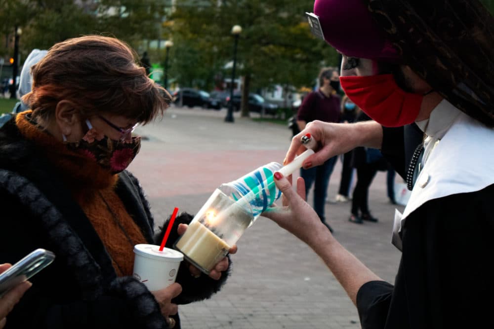 Sister Lida Christ, with the Boston Sisters of Perpetual Indulgence, lights a candle for Gail Miller during a vigil for the late Justice Ruth Bader Ginsburg in Boston's Copley Square. (Adrian Ma/WBUR)