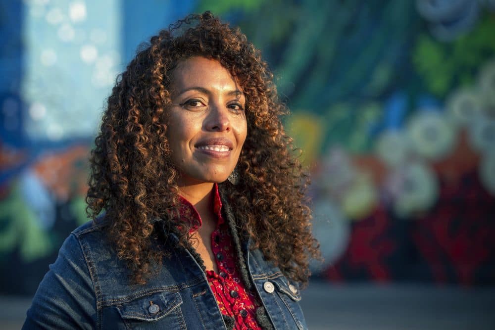 Artist Silvia López Chavez by her mural "Rise" at the Boston Harbor Shipyard and Marina in East Boston. (Robin Lubbock/WBUR)
