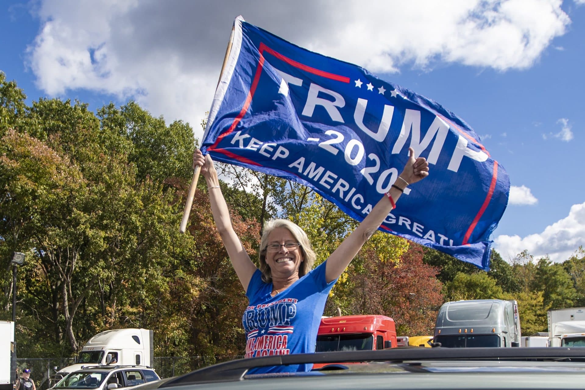 A supporter holds a Trump campaign flag out the sunroof of a car as they leave the Lexington Service Center on Route 95 en route to the Trump Train rally Londonderry, NH. (Jesse Costa/WBUR)
