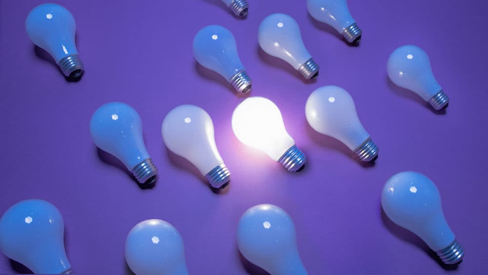 One of 14 incandescent lightbulbs lit on purple surface