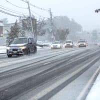 Cars cut tracks through the fresh snow on Waltham Street in Waltham on Friday morning. ( Robin Lubbock/WBUR)