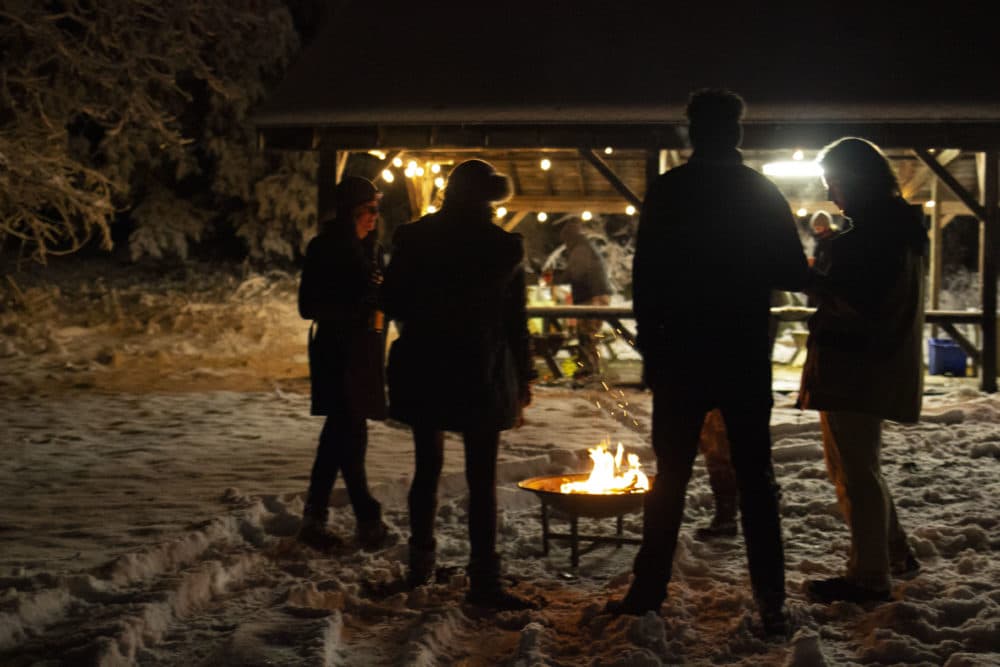 Campers warm up around the fire before the movie begins. (Jenn Stanley/WBUR)