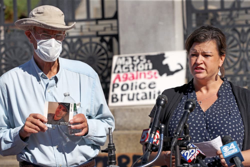 On the steps of the State House on Sept. 4, Jennifer Root Bannon speaks at the podium. Juston's father, Evan Root, holds a photograph of his son. (David L. Ryan/The Boston Globe via Getty Images)